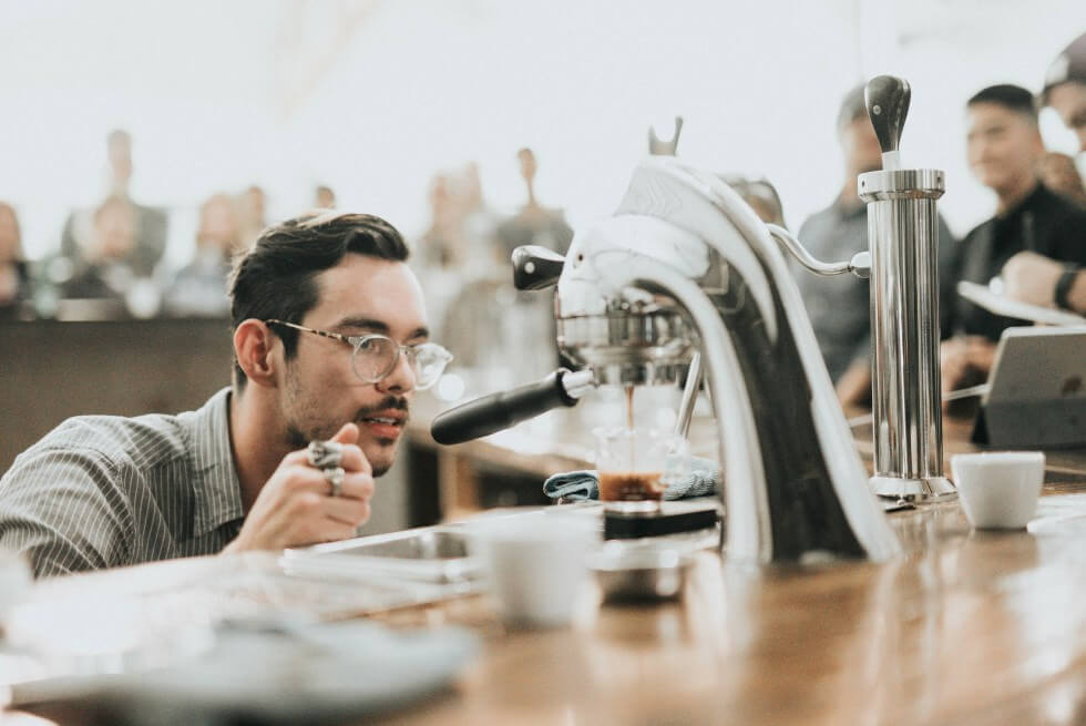 A barista examining an espresso machine.